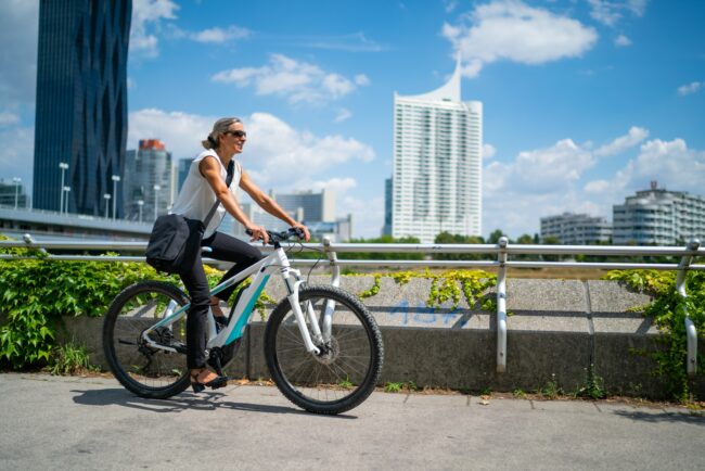 happy businesswoman living sustainable lifestyle cycling on bike to work in city