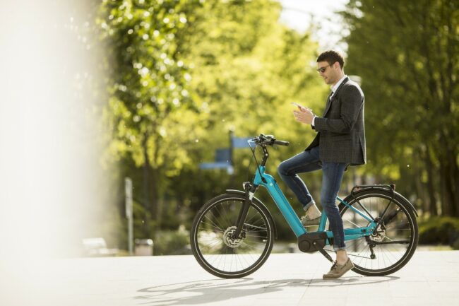 Young businessman on the ebike using mobile phone