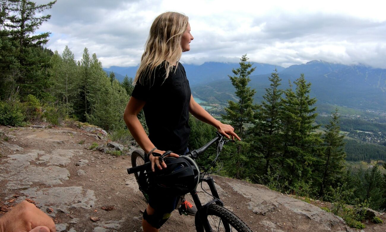 Female mountain biker removes helmet and looks out