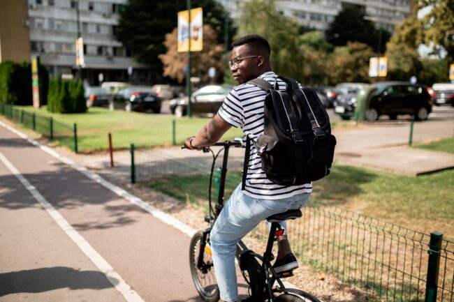 Rear view of a young African American male student riding a bicycle