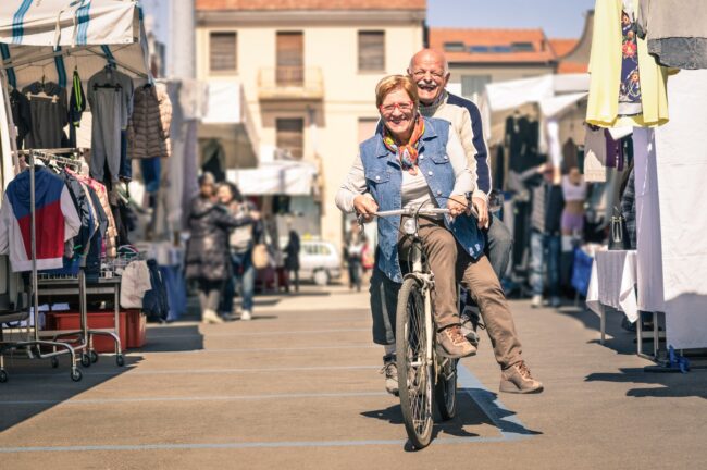 Happy senior couple having fun with bicycle at flea market