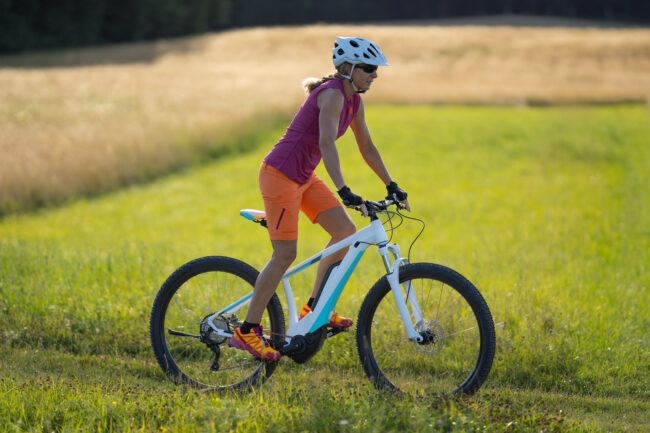 fit woman on electric mountain bike in meadow