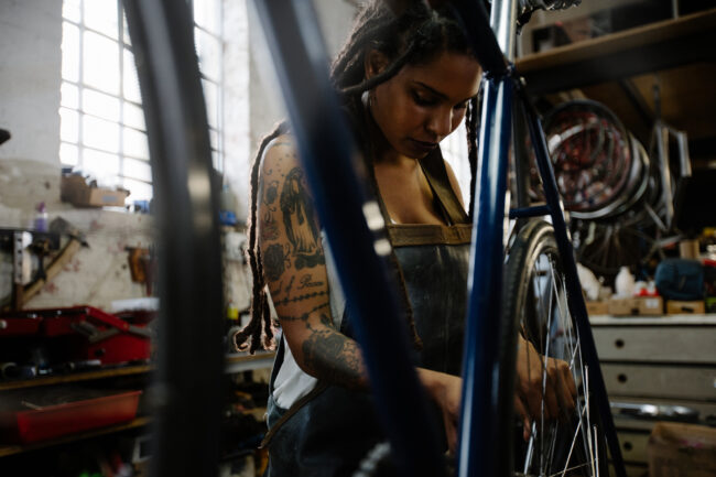 Tattooed female bicycle mechanic working in a repair shop