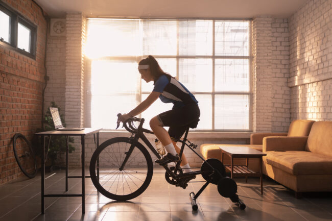 Asian woman cyclist. She is exercising in the house.By cycling on the trainer and play online bike games